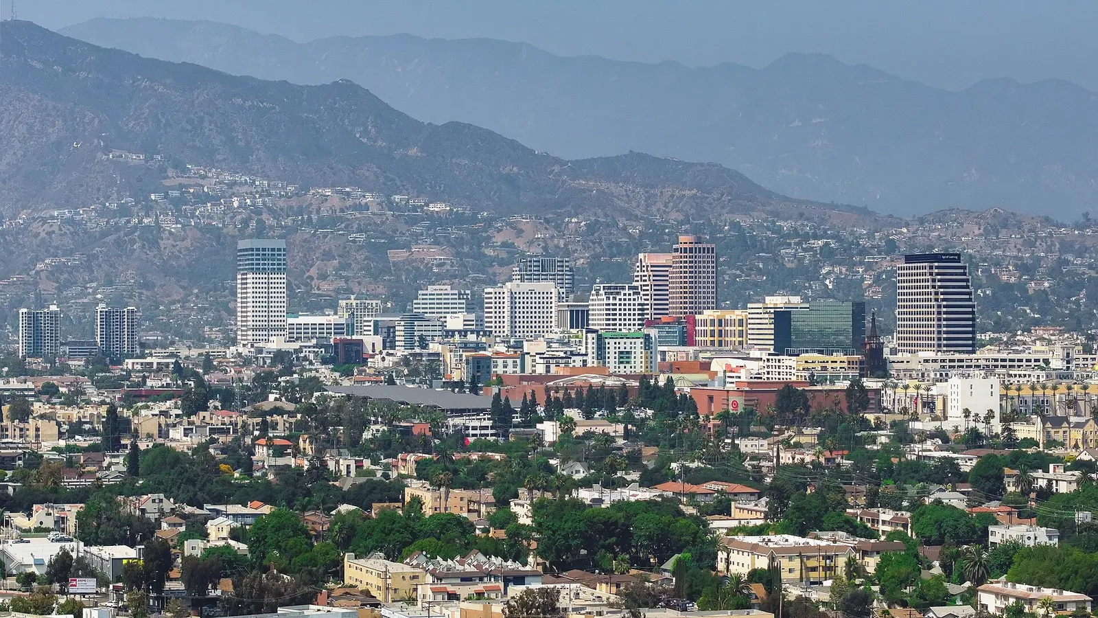 Downtown Glendale office towers and tree-lined neighborhoods with the Verdugo Mountains rising behind them.