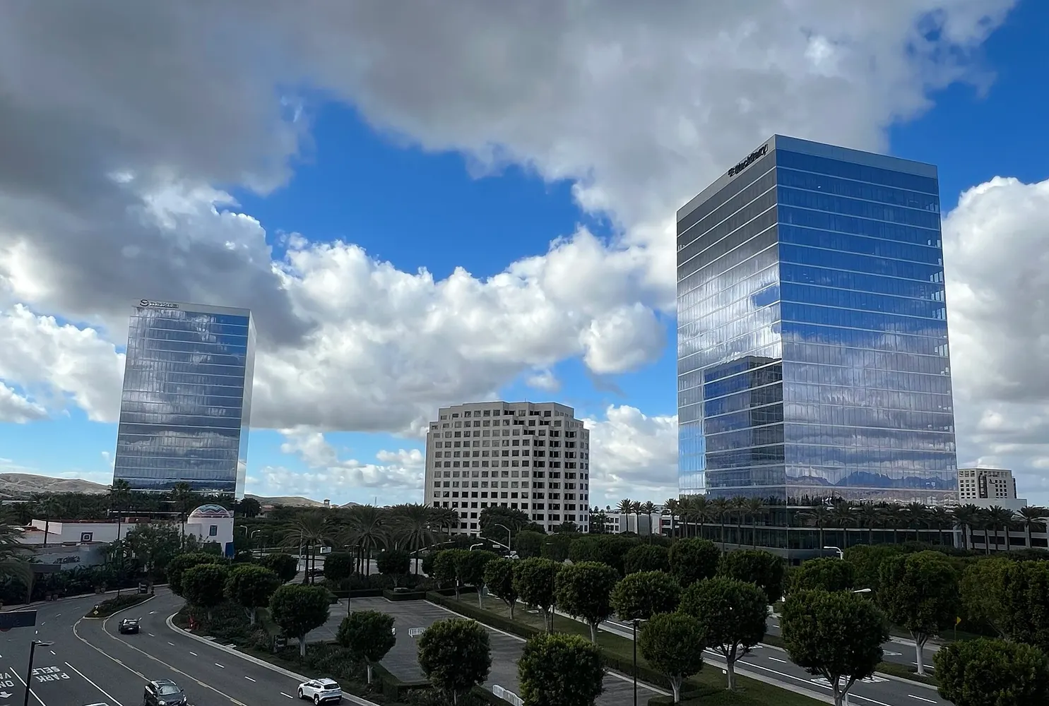 Glass office towers at Irvine Spectrum under a blue sky with white clouds.