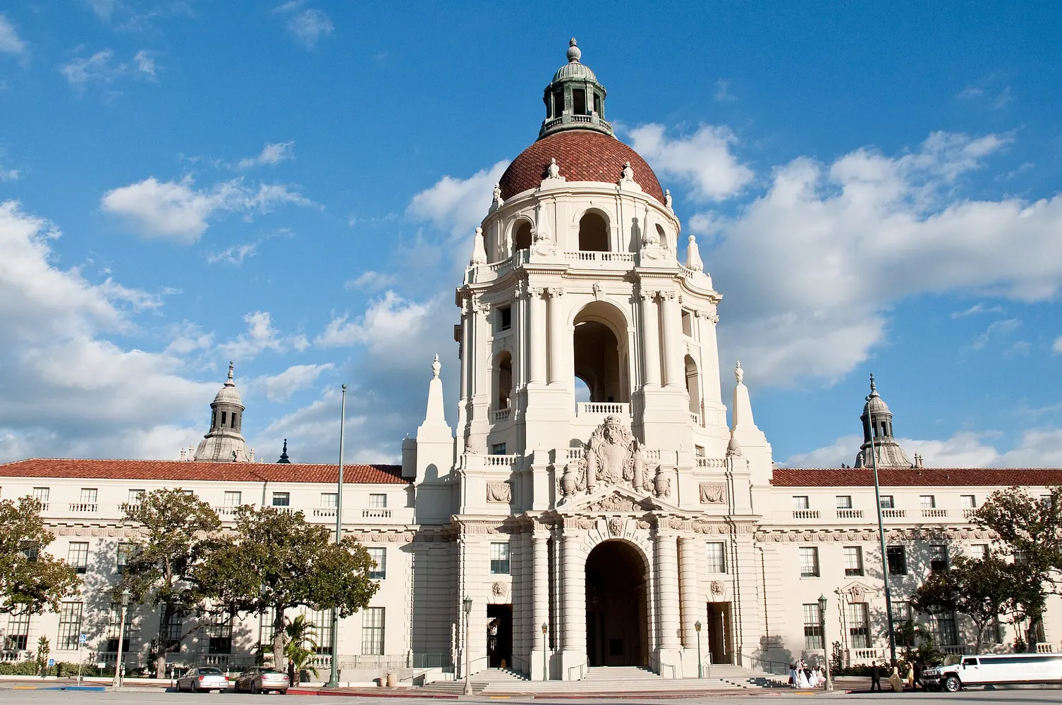 Pasadena City Hall with its domed tower and arched entrance under a blue sky with scattered clouds.